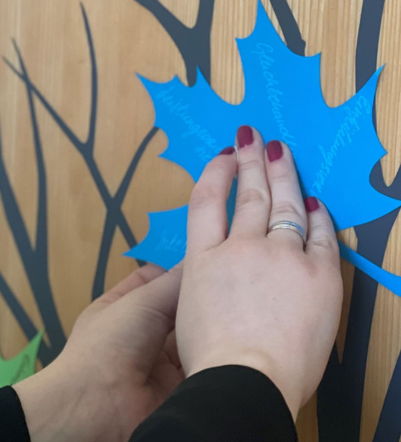 Mitarbeitende befestigt ein Blatt mit ihren individuellen Stärken am Stärkenbaum